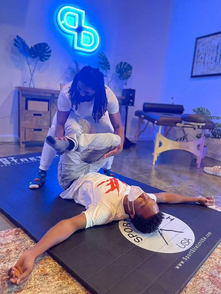 Therapist guiding a client through an assisted stretch on the Pre Bodyworks studio mat