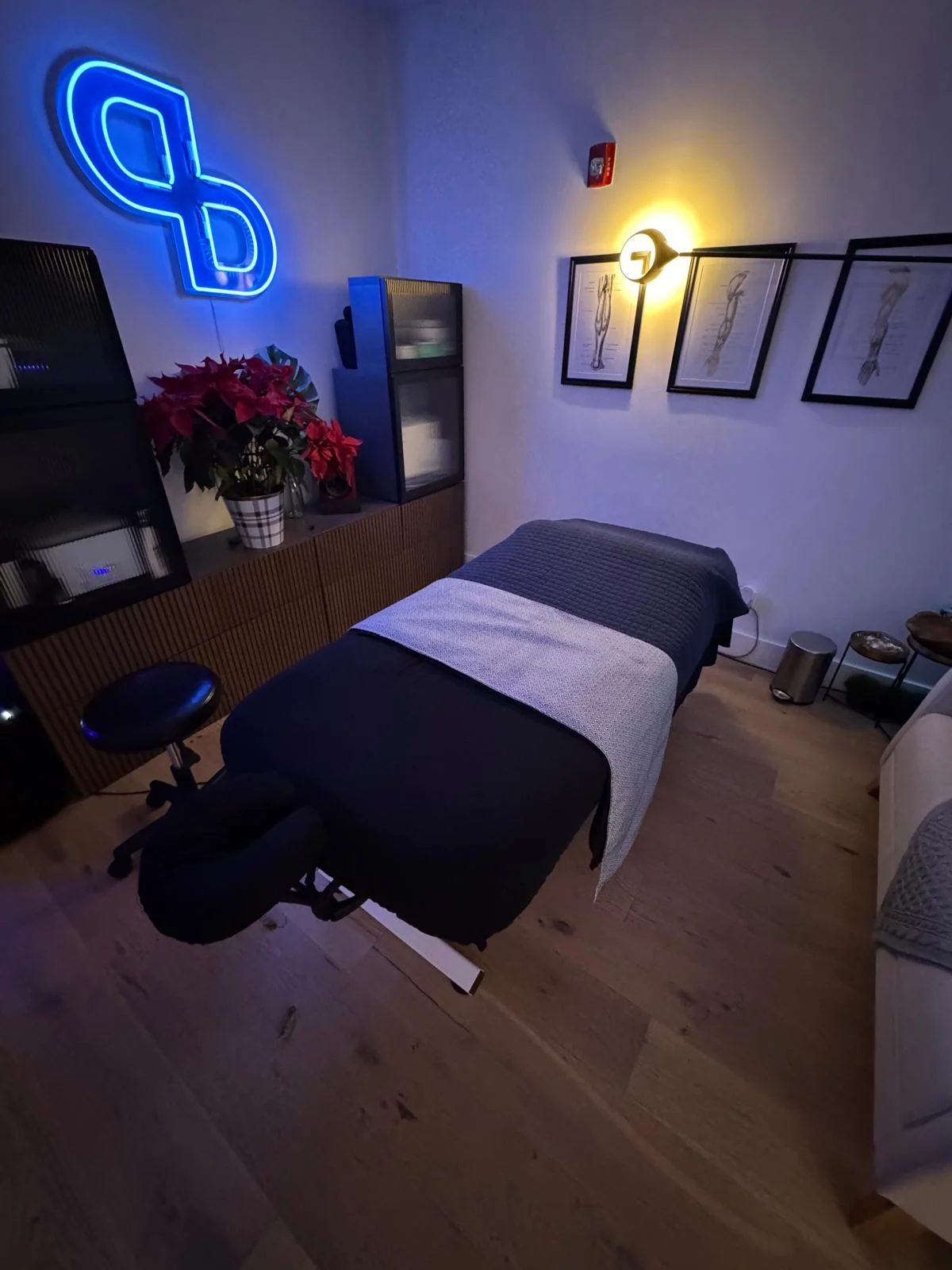 PreBodyworks treatment room with a prepared table and illuminated blue PB monogram